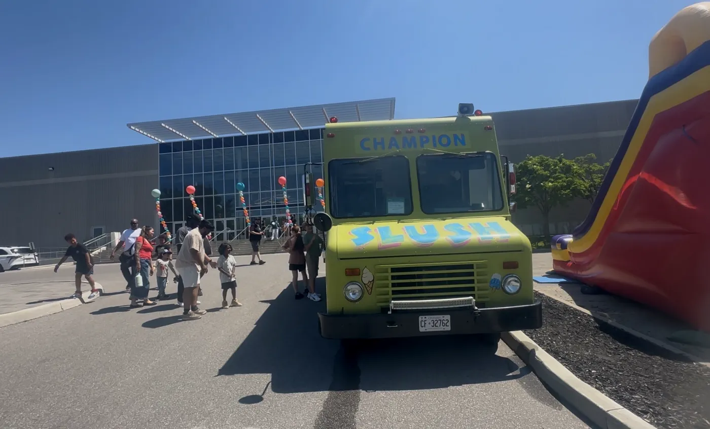 Champion Ice Cream truck at a community event with families lined up