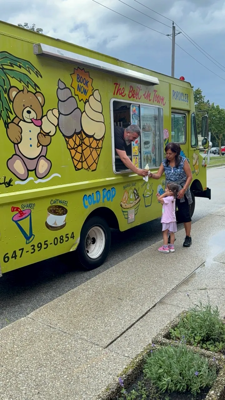 Champion Ice Cream owner serving a soft serve cone through the truck window